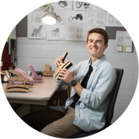 A male product design major sits at his desk working on a woodworking project.